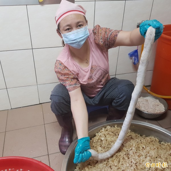 員工將攪拌過紅蔥頭、油蔥與豬油等秘方的糯米飯,用人工灌入大腸圈內。(記者俞肇福攝) 員工將攪拌過紅蔥頭、油蔥與豬油等秘方的糯米飯,用人工灌入大腸圈內。(記者俞肇福攝)