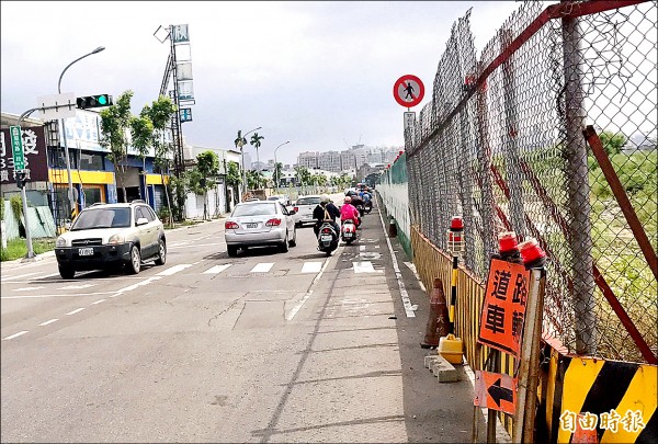 南屯區黎明路施工圍籬設在機車道旁，騎士被迫靠近汽車道，險象環生。（記者張菁雅攝）