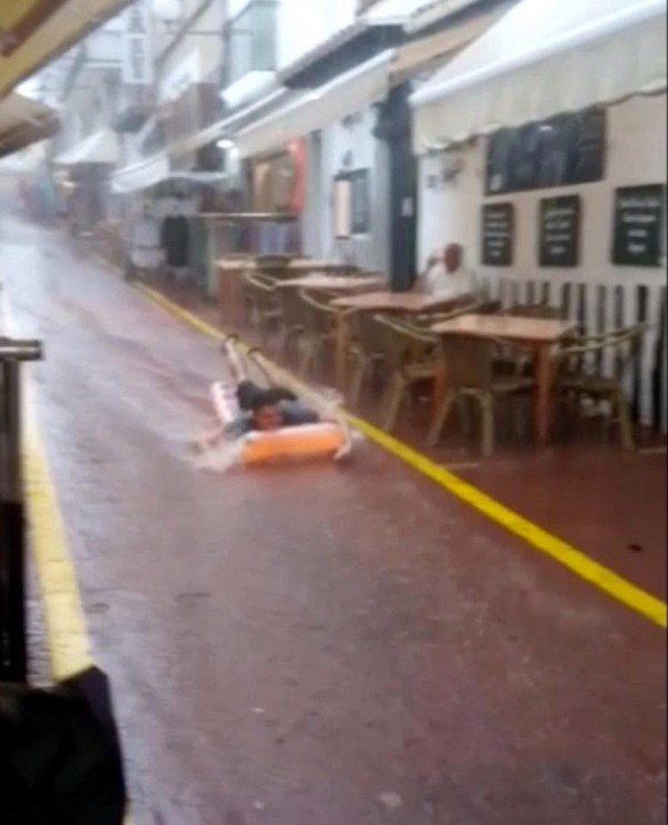 伊比薩島（Ibiza）連日暴雨，一名男遊客為了娛樂母親將淹水的坡道當作滑水道來玩樂。（圖取自太陽報《thesun》）