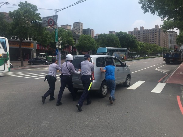 3名員警合力將拋錨的休旅車推至路邊。（記者曾健銘翻攝）