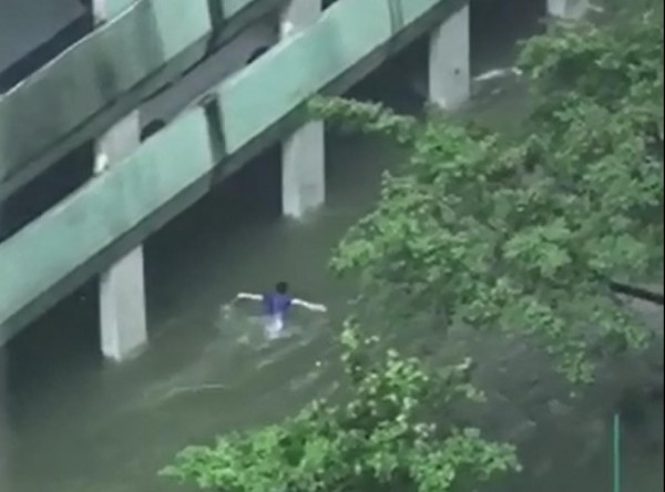 該男子在淹水的道路上游蝶式，被誤以為是在苦中作樂。（圖片擷取自影片）