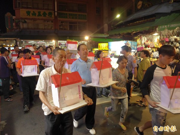 蘆洲區各里里長手捧小水燈頭，緊跟著遶境隊伍中。（記者李雅雯攝）