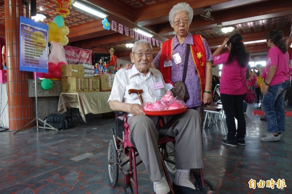 百歲人瑞李福堂發壽桃，92歲妻子管文英緊隨在旁。（記者劉曉欣攝）