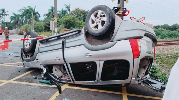 休旅車翻車，車頭在平交道柵欄內，幸好不影響火車通行。（記者楊金城翻攝）