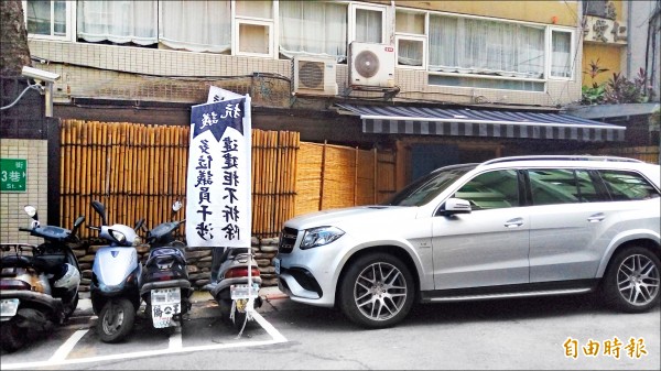 信義區知名日式料理店違規將停車位裝修為庭園造景，並堵住防火巷，遭居民插旗抗議。（記者黃建豪攝）