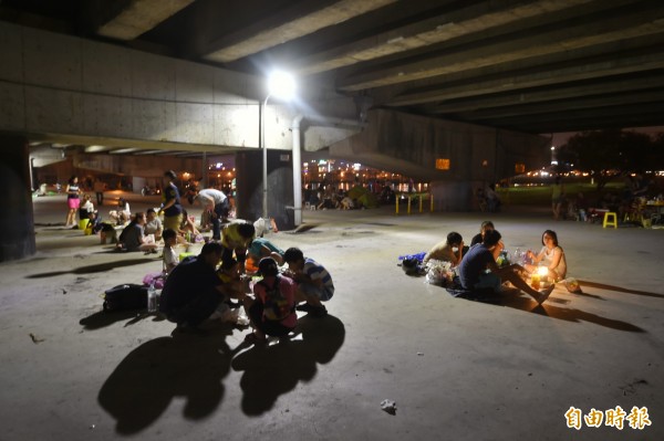 中秋夜雖然天公不作美，但民眾仍在河濱公園橋下烤肉過節。（記者方賓照攝）