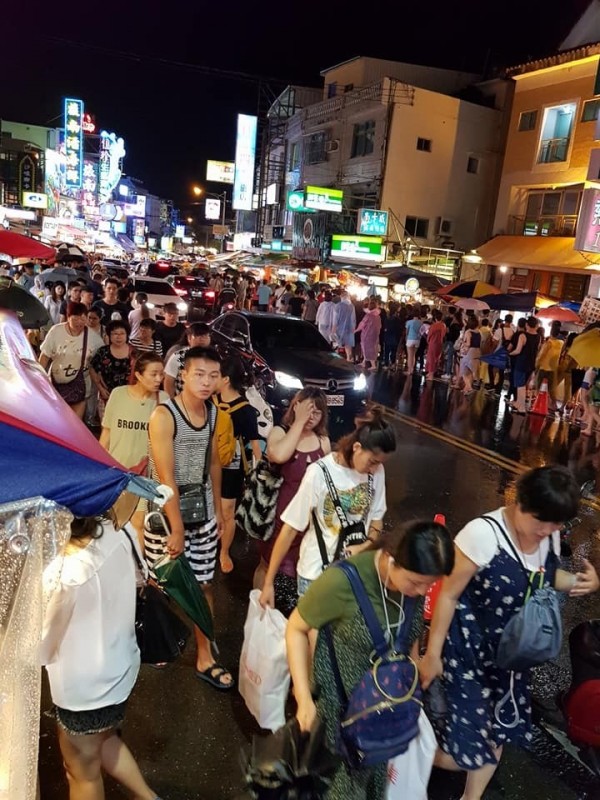 恆春半島陰雨不斷，遊客冒雨逛墾丁大街。（記者蔡宗憲翻攝）