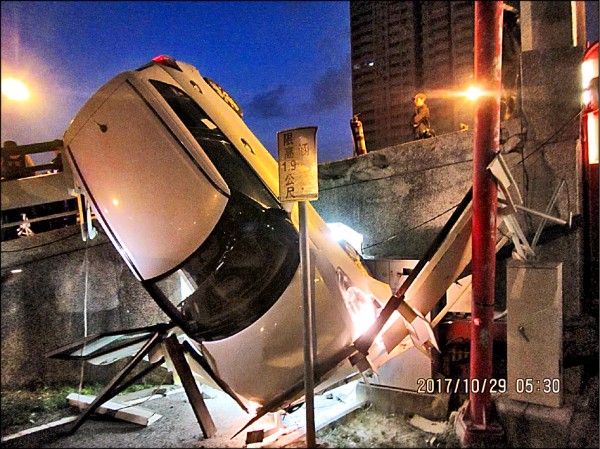 男子酒駕失控自撞中都橋護欄，整部車倒掛在高雄愛河邊自行車道上。（記者方志賢翻攝）