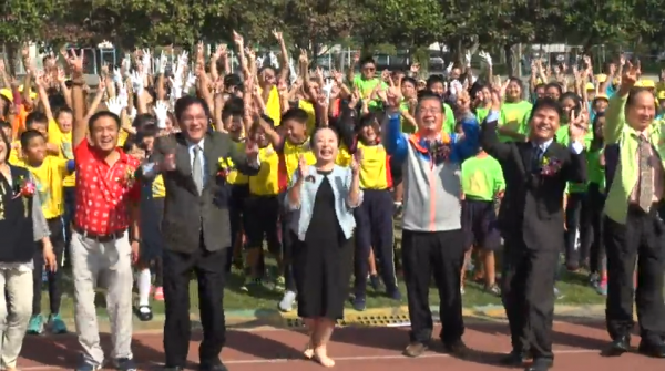 嘉義太保國小新建校舍落成，縣長張花冠今受邀出席剪綵典禮。張與學童們合照時，還率性脫掉高跟鞋，拋高「擲筊」得到「笑杯」。（嘉義縣政府提供）