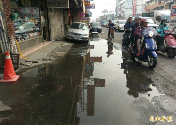 大里區中興路一段在祥全路口附近排水側溝阻塞，積水淹到車道影響商家出入和汽機車通行，市議員蘇柏興要求市府儘快解決。（記者陳建志攝）