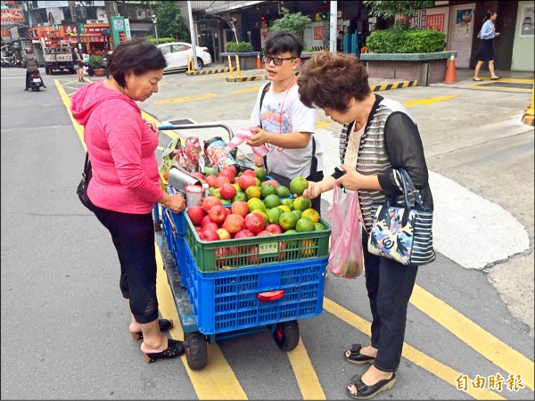 半癱青年劉偉傑為一圓「大學夢」，每天走20公里一拐一拐拖著載滿水果的推車，沿街賣水果。（記者曾健銘攝）