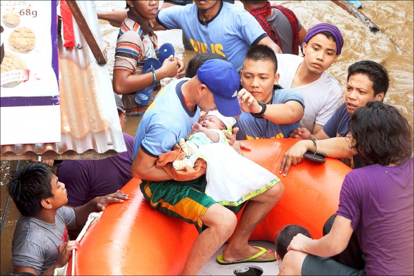 民答那峨北部的卡加延河22日暴漲，迫使卡加延市居民遭緊急疏散，圖為警察抱著襁褓幼兒，執行疏散任務。（法新社）