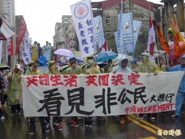 「看見非公民」移工大遊行在滂沱大雨中前進。（記者李雅雯攝）