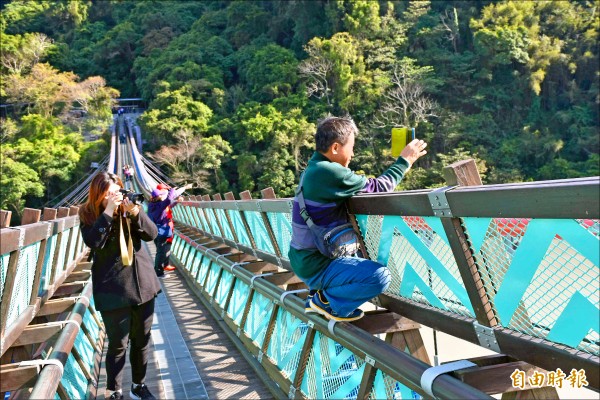 新溪口吊橋剛啟用，遊客為捕捉美景攀爬蹲在欄杆上拍照，讓人看了不禁為他捏一把冷汗。（記者李容萍攝）