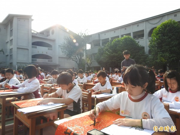 草屯鎮炎峰國小全校學童齊聚操場，揮毫寫春聯。（記者佟振國攝）