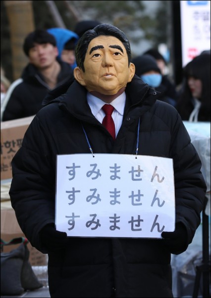 日本首相安倍晉三宣布將出席平昌冬奧並將與南韓總統文在寅舉行會談。圖為24日在南韓首爾街頭群眾戴著安倍面具，要求日本正式對南韓慰安婦道歉。（歐新社）