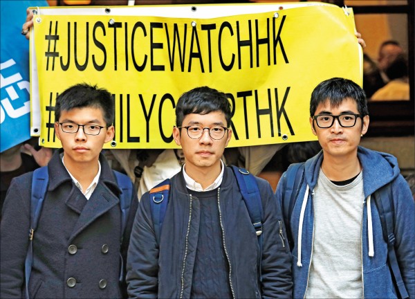 雨傘運動三名學生領袖，二十二歲的黃之鋒（左）、二十五歲的羅冠聰（中）與二十八歲的周永康上月步出香港終審法院的神情。（美聯社）