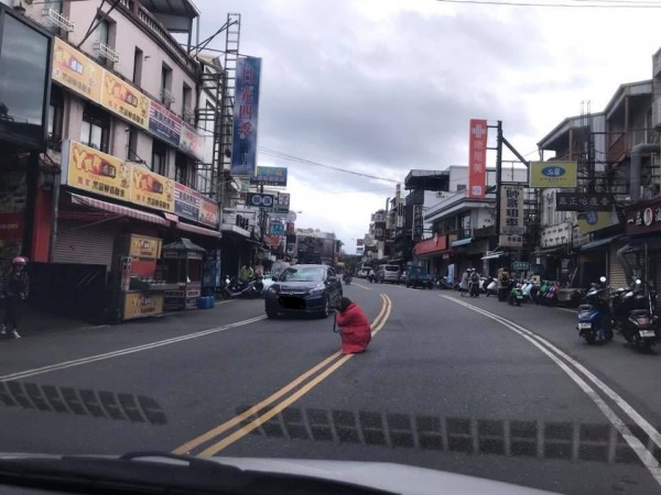 女子蹲在墾丁大街路中央拍照，不顧雙向來車，場面危險。（圖擷取自臉書社團「爆料公社」）