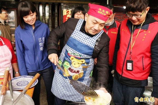 新北市副市長侯友宜繫上圍兜，下廚炒了一盤高麗菜，並與獨老共餐。（記者邱書昱攝）