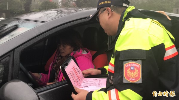 圖左駕駛人從員警手中接過「紅單」，一度面色凝重，後來發現是新埔分局宣導替代道路的妙招，也忍不住笑了。（記者黃美珠攝）