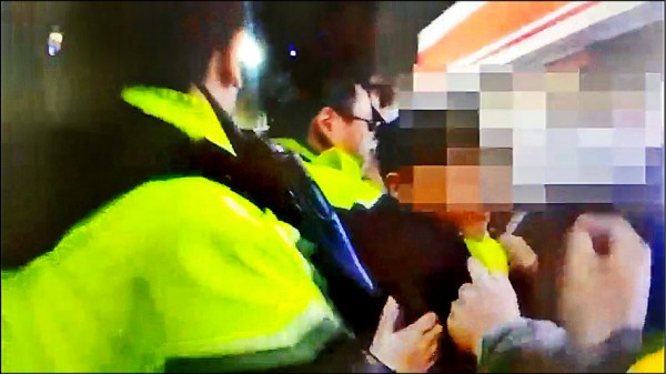 滋事民眾與警方發生拉扯推擠，被帶回警局。 （記者王宣晴翻攝）