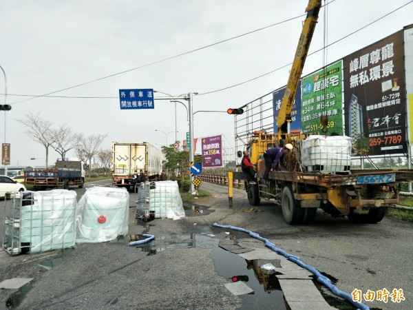 4氫氧化鉀儲桶跌落地面，消防人員先以海綿圍堵避免污染擴大。（記者劉婉君攝）