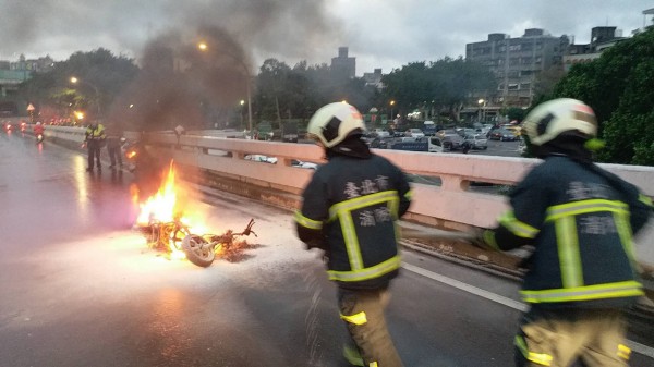 騎士疑因天雨路滑，在百齡橋上自摔，機車卻起火燃燒。（記者陳恩惠翻攝）