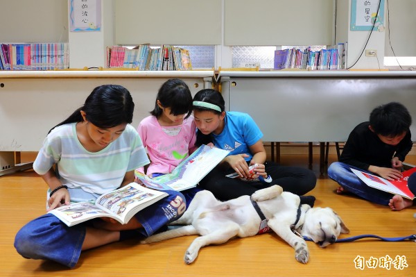 彰化縣文德國小推動陪伴犬閱讀計畫，透過陪伴犬增進學子閱讀與朗誦的興趣，也學習到如何陪伴動物，落實生命教育。（記者李惠洲攝）