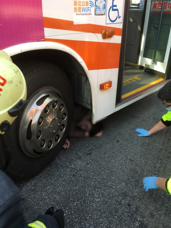 機車駕駛受困公車右前輪。（民眾提供）