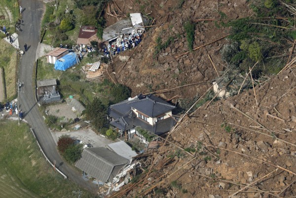 日本九州今凌晨發生土石流，共有3棟民宅被土石掩埋，救難人員稍早挖出1具男性罹難者的屍體。（路透）
