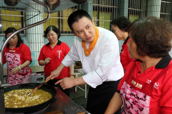 曾擔任飯店主廚的陳建樺（白衣者）專程從南投到五股更新社區，教志工用惜食蔬果製作長輩愛吃的料理。（新北市社會局提供）