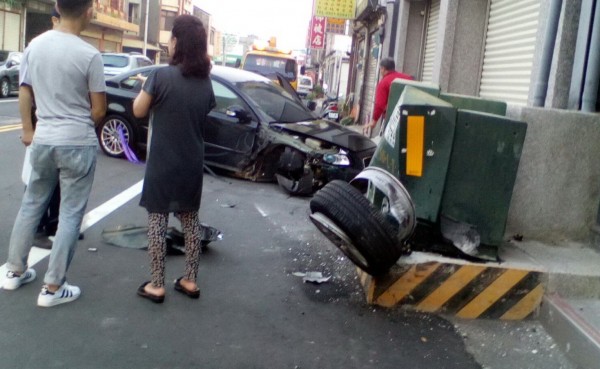 小客車自撞變電箱，車頭受創嚴重，右前輪卡在變電箱上。（記者張勳騰翻攝）