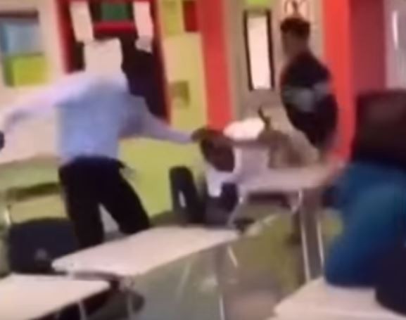 老師將想攻擊他的學生重摔在桌上。（圖擷自YouTube）