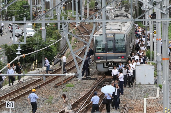 日本關西地區今（18日）發生規模6.1強震，大阪市出現多處災情，但中國觀光客嘖嘖稱奇地說，遇到大地震日本人仍然井井有條。圖為日本民眾依序走出停駛的列車。（法新社）