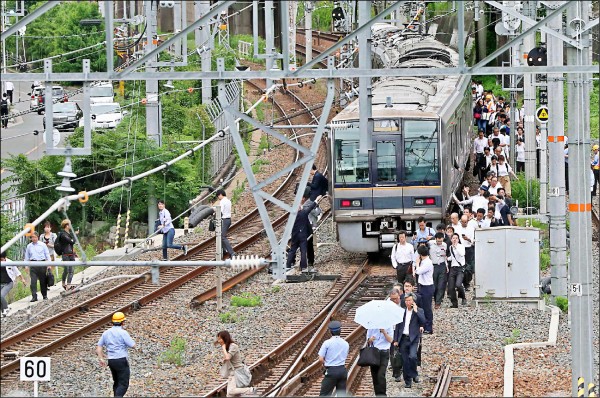 日本大阪十八日上午近八時發生規模六．一強震，當時正值上班上學的通勤尖峰時間，由於餘震頻繁，行駛中的電車隨即停駛，乘客下車沿著鐵軌撤離。（法新社）