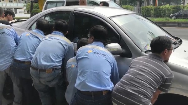 10多名壯漢在轎車兩邊合力抬車。（記者張聰秋翻攝）