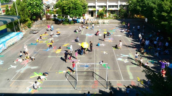 八堵國小開學，學生們躺在地上，由家長或同儕幫忙用粉筆畫下身形，作為另類的身高記錄。（八堵國小提供）