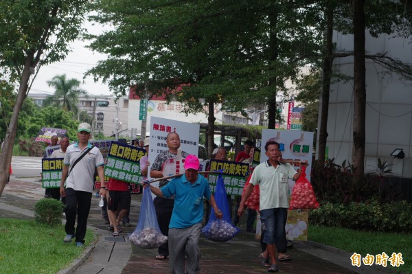 莿桐鄉多位農民扛著蒜頭到縣府抗議進口蒜打壓本土蒜。（記者林國賢攝）