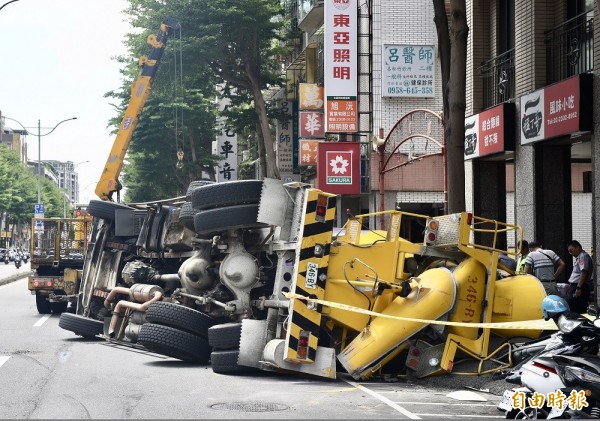 台北市中華路莒光路口23日中午發生一起翻車意外 ，一輛水泥車疑似車速過快，整輛車翻覆在路邊，壓毀停在路邊的汽機車，確切肇事原因仍有待警方調查。（記者羅沛德攝）