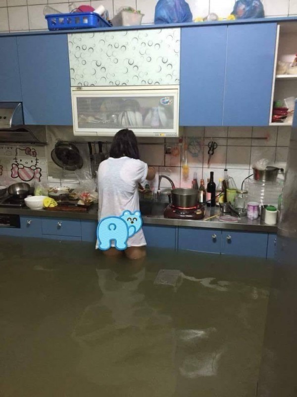 台南媽媽在淹大水的廚房煮飯，讓不少網友淚喊：「媽媽好辛苦！」（圖擷自「爆料公社」臉書粉絲頁）