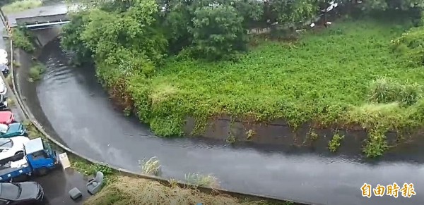 竹南鎮竹興國小後方的射流溝經連日大雨，溪水顏色呈黑褐色，水面上還漂著油汙。（記者鄭名翔攝）