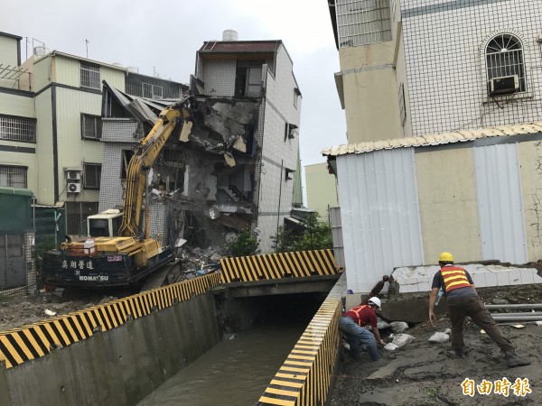 高市府拆除傾斜危屋，同時在溝渠淘空處加強堆置沙包。（記者洪臣宏攝）