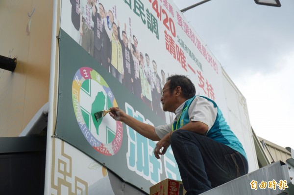 退黨參選的北區議員參選人游金隆自己擦油漆塗銷競選看板上的黨徽等政黨記號。（記者蔡淑媛攝）                     