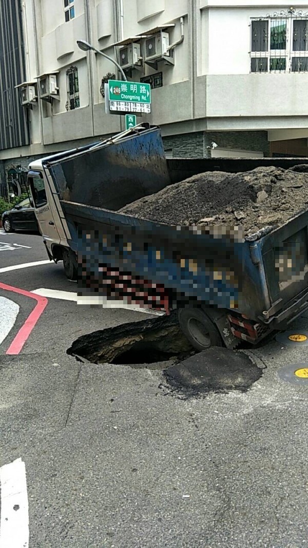 一輛砂石車行駛時左後輪陷入南市東區崇明路、崇明四街口的塌陷路面坑洞。（記者王俊忠翻攝）