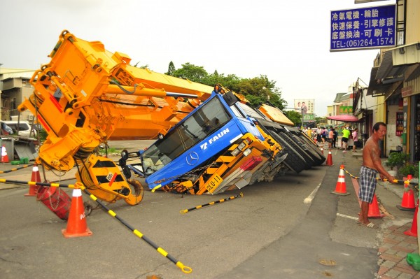 因為賠償問題談不攏，百噸吊車早上中「陷阱」，目前入夜了仍被吃人路咬住不放。（記者王捷攝）