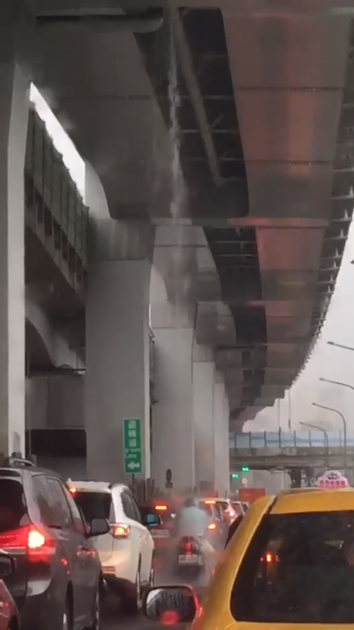 一名機車騎士在高架橋下，任憑暴雨狂灌他的頭頂。（圖擷取自爆廢公社）