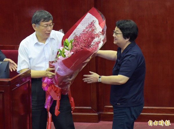 台北市議會13日進行第12屆市政總質詢最後一日，會議結束後，台北市長柯文哲（左）送花束給「畢業」的議長吳碧珠（右）。（記者黃耀徵攝）