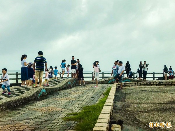 遊客趁著雨停到海邊觀浪。（記者蔡宗憲攝）