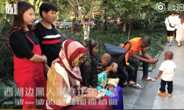 一個非裔家庭原本坐在路邊休息，卻有中國客跑來要合照，讓他們相當尷尬。（圖擷自微博）
