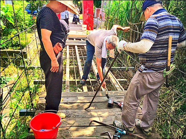 義仁社區及灣橋北極殿志工協助汰換義仁吊橋木棧板。（竹崎鄉公所提供）